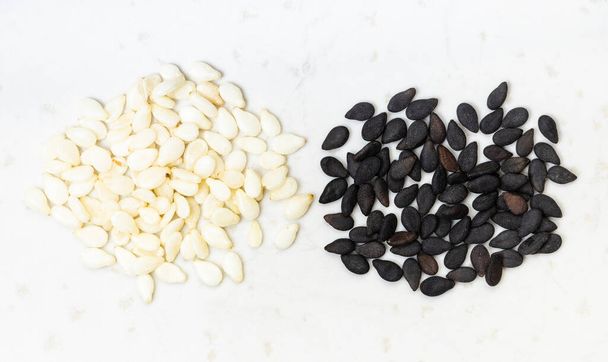 вид сверху на черно-белые семена кунжута близко на серой керамической пластине - Фото, изображение