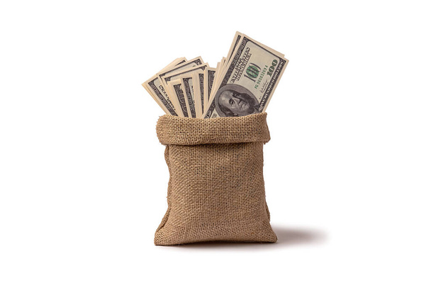Un saco de arpillera con dólares está sobre un fondo blanco. Inversiones y finanzas. - Foto, Imagen
