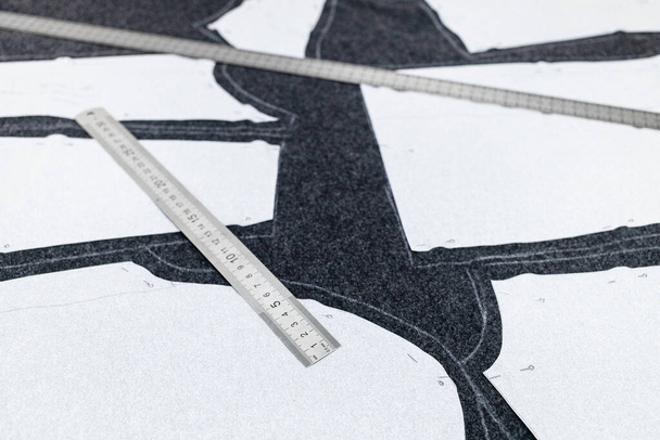 компоновка узора шитья платья и стальной линейки крупным планом на темной ткани - Фото, изображение