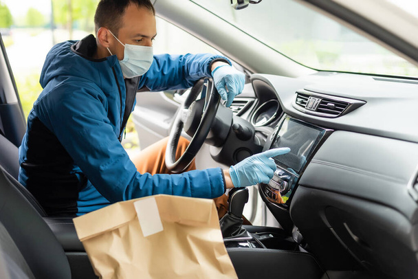 Kargo aracının önünde koruyucu maske takan postacı Coronavirus hastalığı veya COVID-19 nedeniyle paket teslim ediyor. - Fotoğraf, Görsel