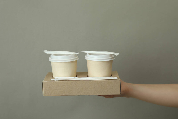 Female hand hold paper cups on gray background - Photo, Image
