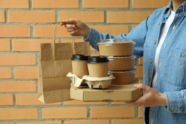 Woman hold delivery containers for takeaway food on brick wall background - Photo, Image