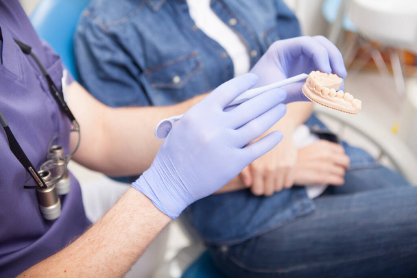 Unrecognizable dentist showing dental mold to the patient - Fotó, kép