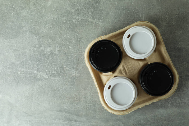 Cup holder with coffee cups on gray textured background - Foto, Bild