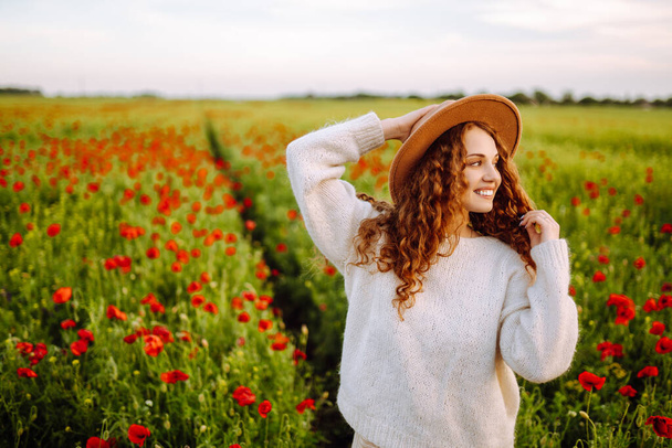 Young woman walking in amazing poppy field. Summertime. Beautiful woman posing in the blooming poppy field. Nature, vacation, relax and lifestyle. - Fotoğraf, Görsel