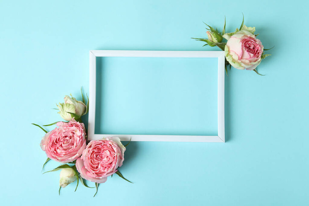 Roses and empty frame on blue background, space for text - Zdjęcie, obraz