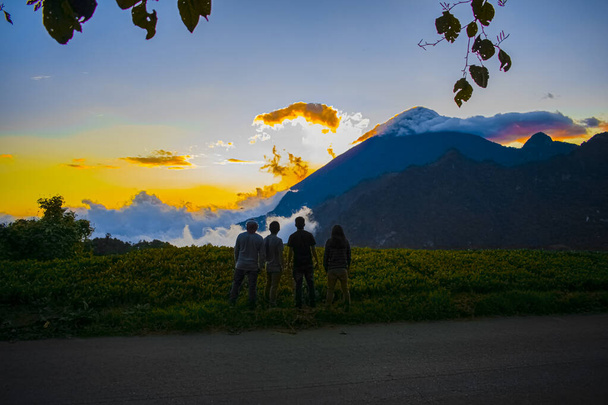 jeunes regardant le coucher du soleil avec le volcan en arrière-plan - Photo, image