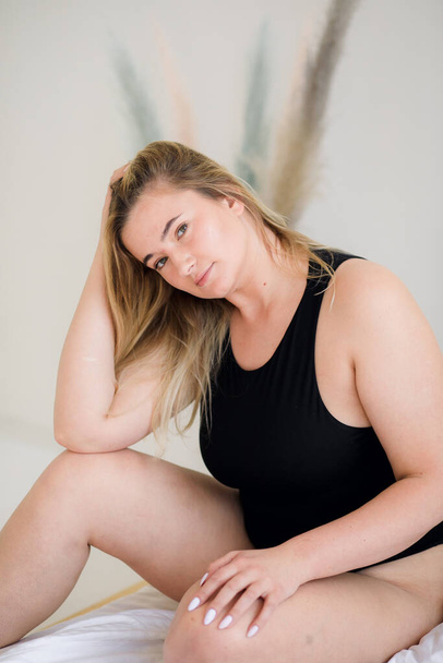 Beautiful overweight woman in black swimsuit on grey background - Photo, Image