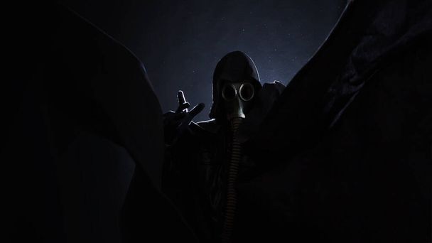 post-apocalyptic angel of death, a scary story, a concept character in a gas mask and a black raincoat - Fotografie, Obrázek