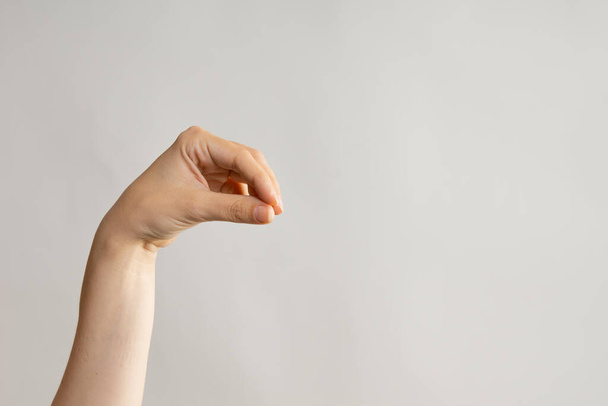 Hand gestures. Elegant female hand holding something with two fingers - Valokuva, kuva