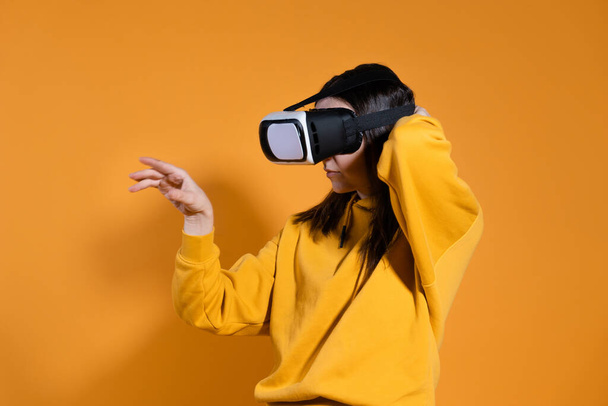 young woman with a virtual reality device on a yellow background. - 写真・画像
