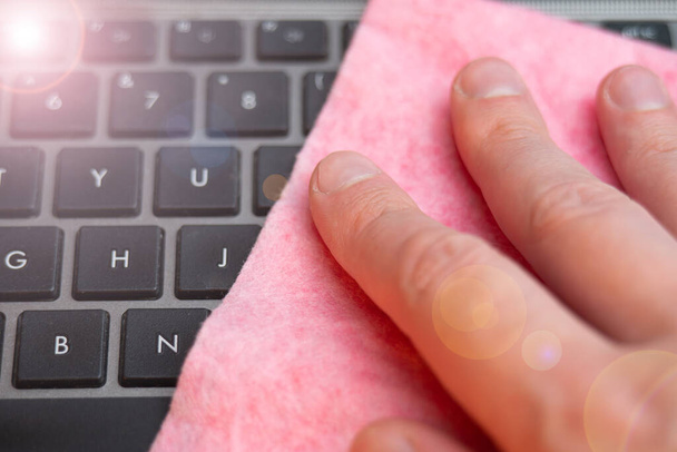 手は湿ったマイクロファイバー布でノートパソコンのキーボードを拭く - 写真・画像