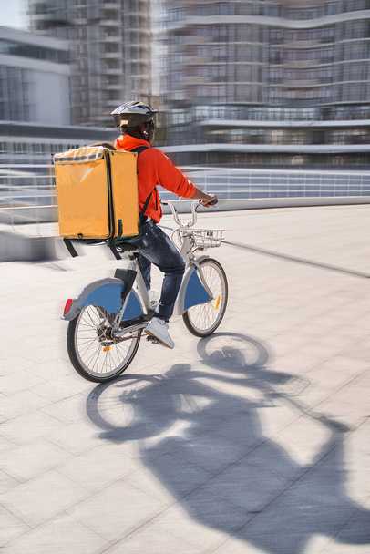 Courier with yellow backpack driving bike and coming to the client with parsels - Valokuva, kuva