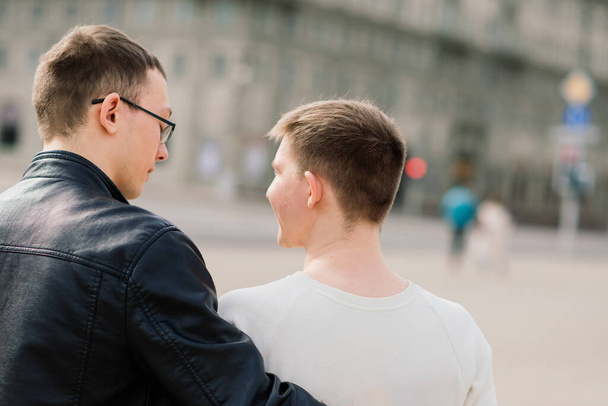 Cute gay couple in a city, tender gentle kissing, smiling - Photo, image