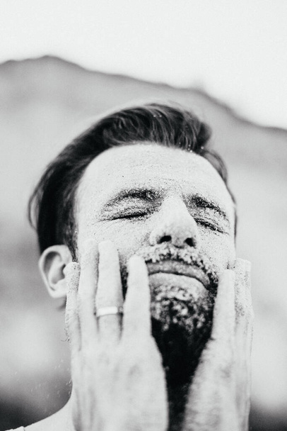 creative portrait of a man with a beard whose face is covered with a layer of sea sand - Foto, Bild