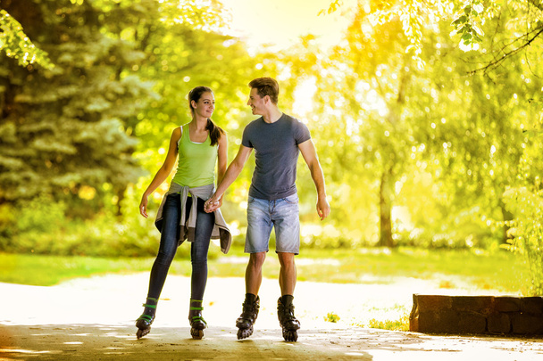Young couple roller-skating in the park - 写真・画像