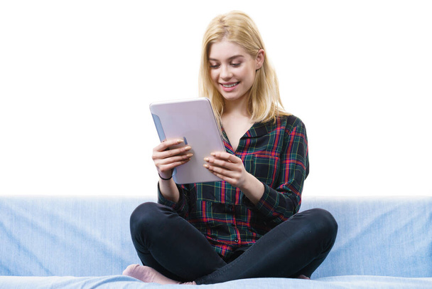Young teenage woman using tablet while sitting on sofa and relaxing surfing on internet - Photo, image