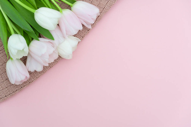 Bouquet of pink pastel tulips on pink knit sweater background, top view of pink tulips bouquet for womans Day, spring flowers concept - Photo, image