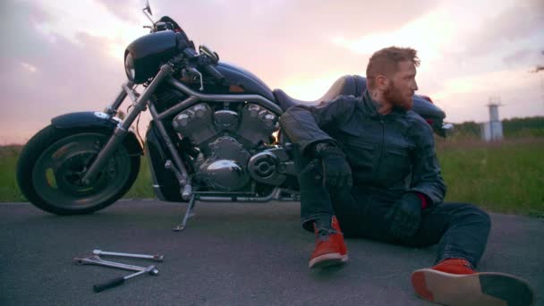Das Motorrad des Motorradfahrers ging kaputt, er sitzt und wartet auf Hilfe - Filmmaterial, Video