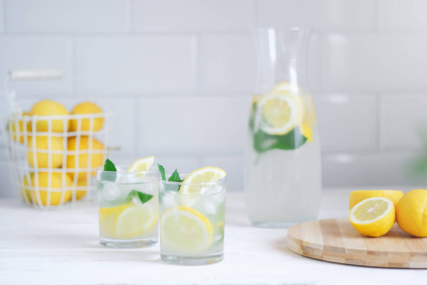 Fresh lemon lemonade with mint in bottle on kitchen table with ingredients. healthy nutrition diet concept. White background - Fotó, kép