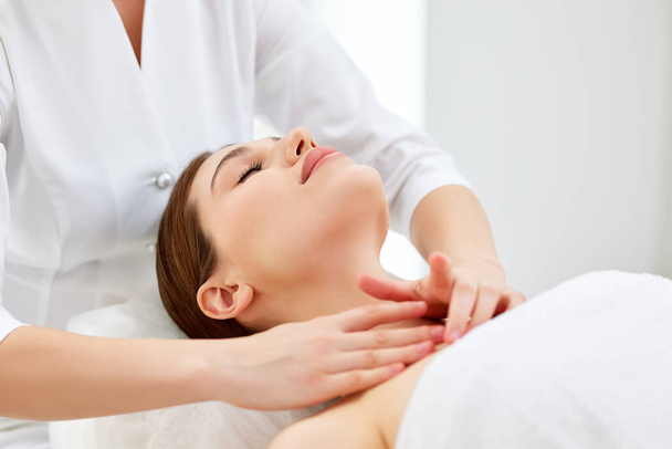Close up of beautician or masseur doing myofascial or buccal head and face massage for young woman. Female patient lying at spa center, receiving anti aging beauty treatment. Skin rejuvenation concept - Foto, afbeelding