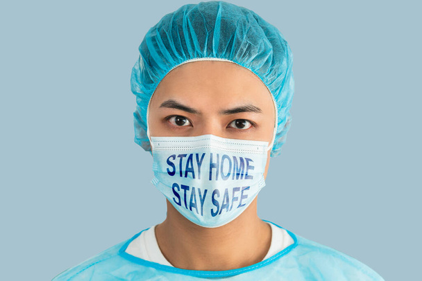 Doctor wear face mask, blue green uniform showing stay home stay safe concepts - Foto, Imagem