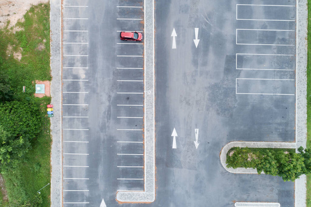 Vista aerea dall'alto verso il basso di SUV rosso auto parcheggiata in cemento parcheggio con linea bianca del segnale stradale sulla strada. Sopra vista della macchina in fila al parcheggio Parcheggio esterno. - Foto, immagini