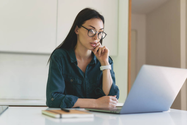 Концентрированная деловая женщина, работающая из дома с ноутбуком и ноутбуком - Фото, изображение