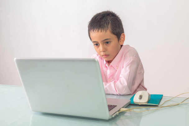 Un niño con una camisa rosa estaba disfrutando viendo el portátil felizmente. Retrato de estudio, concepto con fondo blanco.  - Foto, imagen