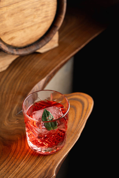 Cóctel agrio clásico con ron y fizz, hermoso cóctel rojo en un mostrador de bar de madera inusual - Foto, imagen