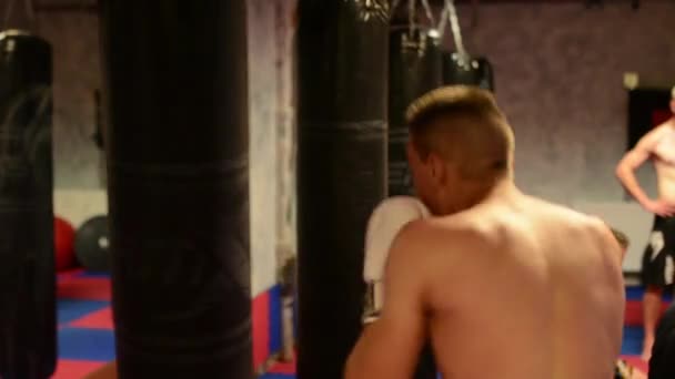 Homens praticam esporte - esportes de combate (boxe no saco) - no ginásio
 - Filmagem, Vídeo