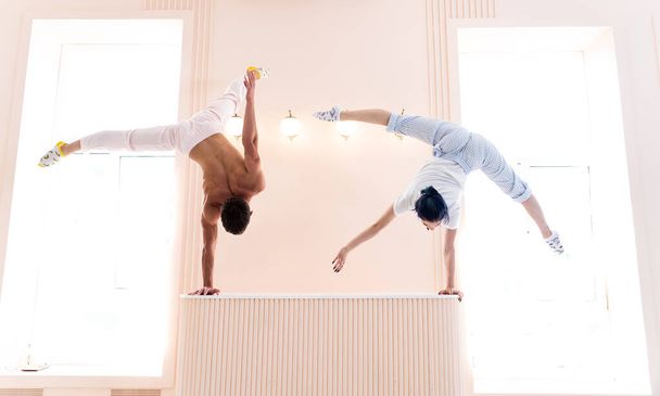 Couple Yoga, man and woman doing high level yoga exercises and handstand indoor. Healthy lifestyle concept  - Фото, зображення