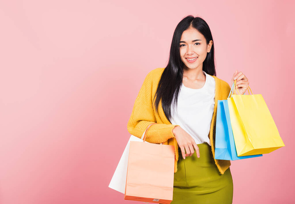 Portrait of Asian happy beautiful young woman teen shopper smiling standing excited holding online shopping bags colorful multicolor in summer, studio shot isolated on pink background with copy space - Foto, imagen