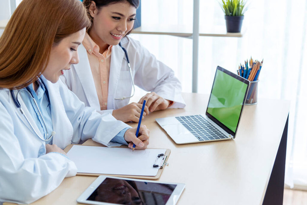 Twee Aziatische vrouwelijke artsen bespreken het ontmoeten van de dokter medische kliniek met behulp van laptop consulting patiënt ziekte. Aziatisch medisch lab jonge vrouwen praten samen over gezondheidszorg bijstand teamwork - Foto, afbeelding
