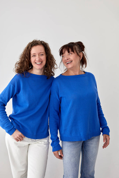 Entzückte Mutter und Tochter in ähnlichen Pullovern im Studio - Foto, Bild