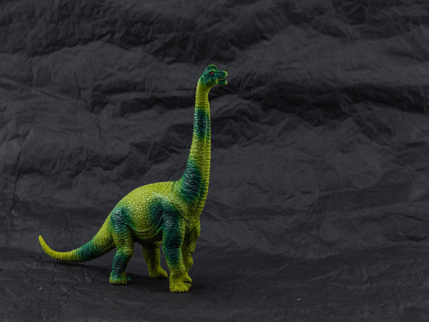 Dinosaurio de juguete de plástico sobre fondo oscuro - Foto, imagen