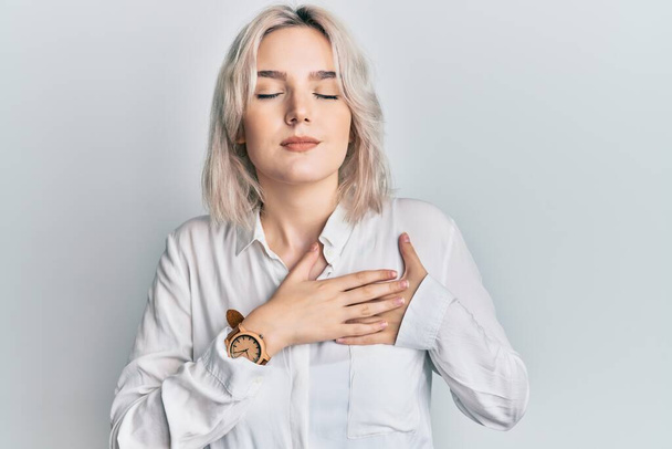 Young blonde girl wearing casual clothes smiling with hands on chest, eyes closed with grateful gesture on face. health concept.  - Фото, изображение