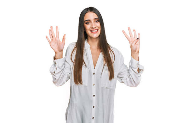 Młoda piękna kobieta w luźnej białej koszuli pokazując i wskazując palcami numer dziewięć uśmiechając się pewny siebie i szczęśliwy.  - Zdjęcie, obraz