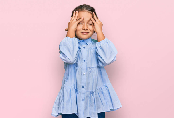 Kis gyönyörű lány visel alkalmi ruhát szenved fejfájás kétségbeesett és stresszes, mert a fájdalom és a migrén. kezeket a fejre..  - Fotó, kép