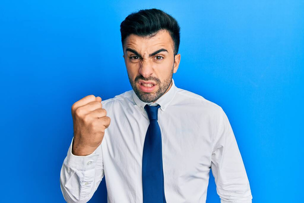 Young hispanic man wearing business clothes angry and mad raising fist frustrated and furious while shouting with anger. rage and aggressive concept.  - Foto, afbeelding