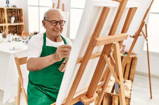 Senior grey-haired artist man smiling happy painting at art studio. - Photo, Image