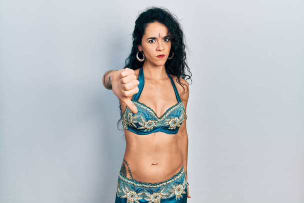 Young woman wearing bindi and traditional belly dance clothes looking unhappy and angry showing rejection and negative with thumbs down gesture. bad expression.  - Photo, Image