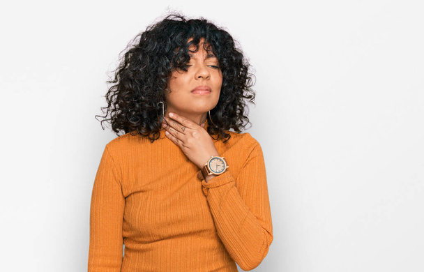 Jeune femme hispanique portant des vêtements décontractés touchant le cou douloureux, mal de gorge pour la grippe, la motte et l'infection  - Photo, image