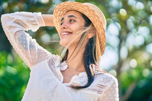Νεαρή Ισπανίδα τουρίστρια με καλοκαιρινό καπέλο που στέκεται στο πάρκο. - Φωτογραφία, εικόνα