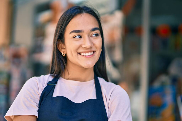 Fiatal latin boltos lány mosolyog boldog áll a sajtóban - Fotó, kép