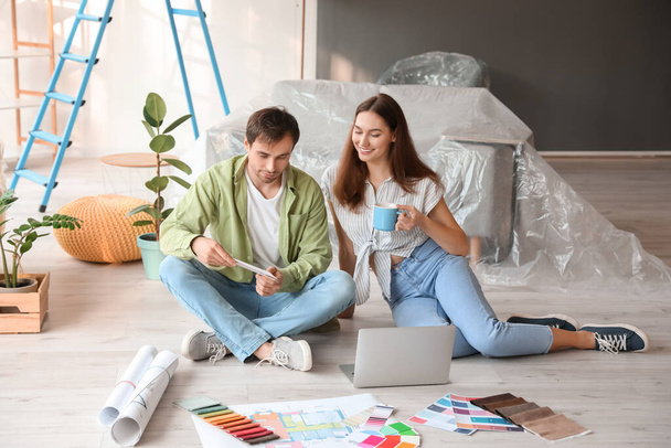 Happy young couple with laptop planning repair in their new house - Foto, Imagen