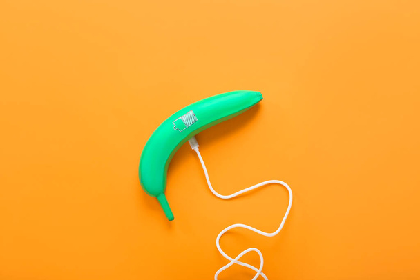 Creative composition with painted banana and USB cable on color background - Photo, Image