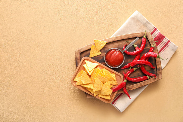 Plateau avec sauce savoureuse, nachos et piments sur fond de couleur - Photo, image