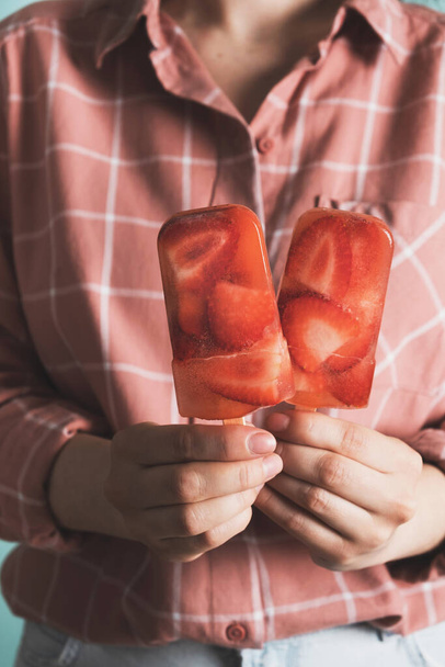 Mulher segurando picolé com morango. Sobremesa refrescante de verão. Fechar, vertical - Foto, Imagem