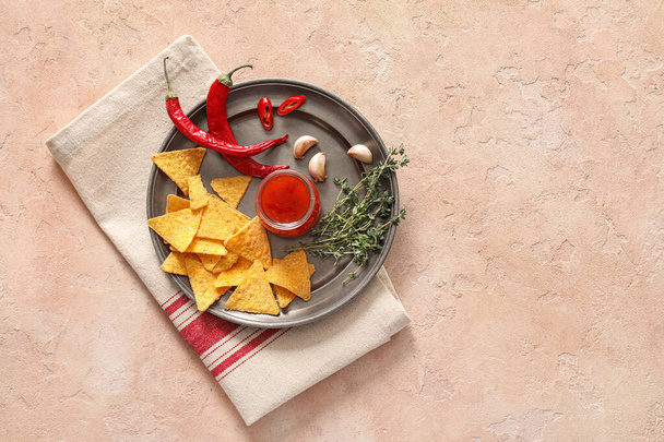 Plateau avec sauce chili savoureuse, nachos et ingrédients sur fond de couleur - Photo, image